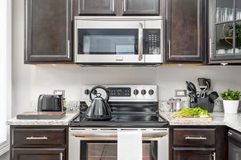 Kitchen with white appliances and black cabinets and a white stove and microwave